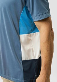 Short-sleeve polo shirt featuring a combination of light blue, white, and dark blue sections with a smooth texture and athletic fit.