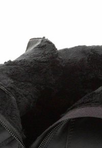 Czarne skórzane botki za kostkę charakteryzują się miękką, czarną podszywką z sztucznego futra, widocznym zamkiem błyskawicznym oraz zaokrąglonym noskiem. Wnętrze ma luksusową teksturę.