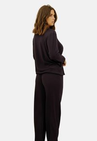Ensemble de détente violet foncé avec une texture côtelée, un haut à manches longues et un pantalon ample, conçu pour le confort et la relaxation.