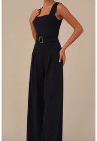 Námořnický overal se čtvercovým výstřihem, širokými nohavicemi, sklady a páskem v pase s obdélníkovou kovovou sponou.