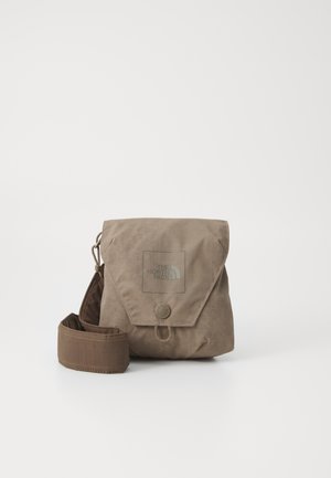 Petit sac bandoulière beige avec rabat, bouton et sangle réglable, avec le logo The North Face sur le devant.