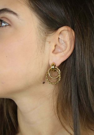 Złote kolczyki koła z dwoma połączonymi kółkami, jednym gładkim i jednym skręconym, z teksturowanym wykończeniem i polerowanymi akcentami.