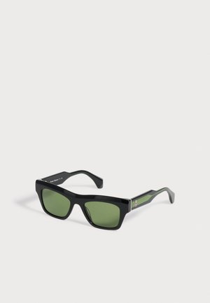 Lunettes de soleil rectangulaires noires avec des verres verts et un petit emblème de planète argenté sur la branche.