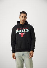 Felpa nera in misto cotone, con la scritta "CHICAGO BULLS" in rosso e verde e un logo di un toro rosso. Tasca a marsupio sul davanti.