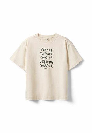 T-shirt beige à manches courtes avec texte noir : "YOU'RE AWFULLY GOOD AT DECEIVING YOURSELF" et texte plus petit "Little My" en dessous.