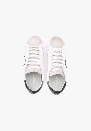 Sneakers bianchi con dettagli in suede e tallone nero. Presentano lacci e punta rotonda. Materiale liscio con marchio in rilievo all'interno.