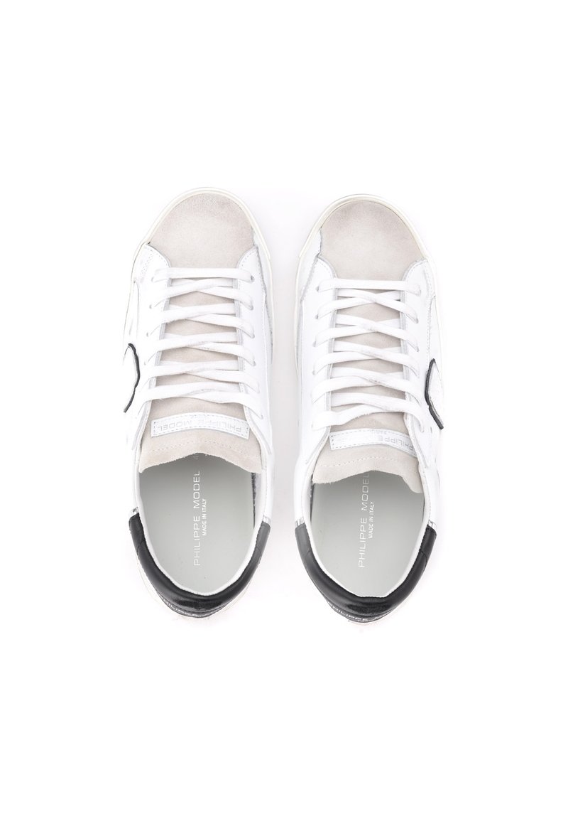 Sneakers bianchi con dettagli in suede e tallone nero. Presentano lacci e punta rotonda. Materiale liscio con marchio in rilievo all'interno.