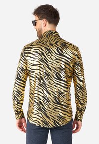 Chemise à manches longues noire et dorée à motif, avec une finition brillante, présentant des rayures de tigre, des poignets à boutons et un col évasé.