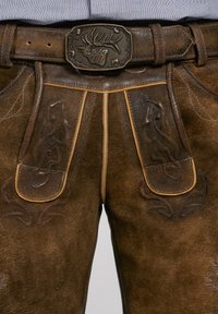 Bruna läderlederhosen med intrikata präglade mönster, rörsydda sömmar och en dekorativ metallspänne med ett älgdjursdesign.