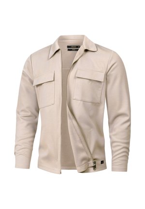 Veste beige à manches longues avec deux poches avant à rabat et une fermeture éclair partiellement ouverte à l'avant, présentée sur un fond blanc.