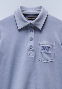 Lichtgrijs poloshirt met kraag, vierknopenknopsluiting, geborduurd logo op de linker borstzak en textiel met textuur.