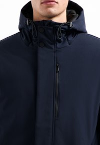 Marineblauwe hoodie-jack met een gladde, matte afwerking. Beschikt over een voorzak met rits en drukknopen, wat het gestroomlijnde ontwerp benadrukt.