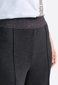 Tamsiai pilki kelnių iš tekstūruoto audinio. Elastinga juosmens juosta su įspaustu logotipo detalizavimu. Įtrauktos elegantiškos šoninės klostės, suteikiančios pritaikytą išvaizdą.
