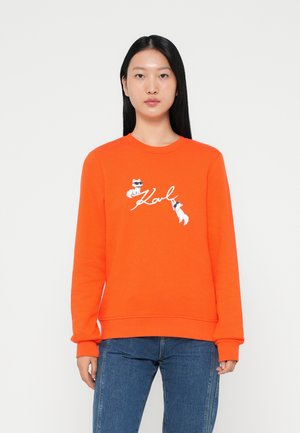Oranje sweatshirt van katoenmix, met geborduurd grafisch ontwerp van katten en het woord "Karl." Ribbelboorden en ronde halslijn.