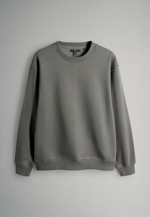 Halli fliisist pusa, mis on valmistatud pehmest kangast, millel on ümara lõike ja kaela, pikad varrukad ning soonikud mansettides ja ääres. Lihtne, kaunistusteta disain.