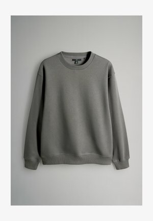 Halli fliisist pusa, mis on valmistatud pehmest kangast, millel on ümara lõike ja kaela, pikad varrukad ning soonikud mansettides ja ääres. Lihtne, kaunistusteta disain.