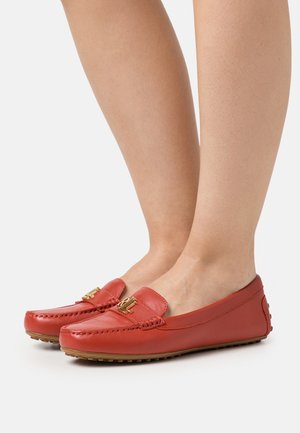 Red leather loafers with stitching details and gold hardware. Rounded toe and flat sole with textured grip.