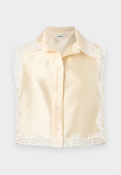 Κρεμ σατέν μπλούζα μπροστά με κλασικό γιακά, κούμπωμα με κουμπιά και δαντελένια διακόσμηση με κυματιστό περίγραμμα κατά μήκος των άκρων.