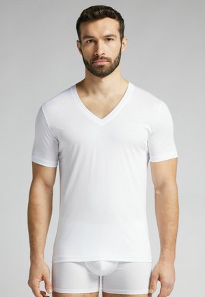 Weißes kurzärmliges V-Ausschnitt-T-Shirt aus glattem Stoff, kombiniert mit weißen, enganliegenden Shorts. Das Shirt hat ein einfaches Design und eine normale Passform.