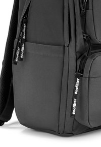 Grau Stoff-Rucksack mit mehreren Reißverschlussfächern, Netzpolsterung an den Trageriemen und schwarzen Reißverschlussanhängern, auf denen der Text "#nofilter" steht.
