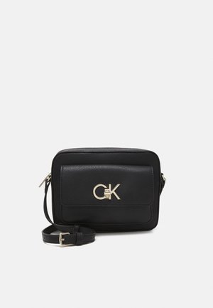 Černá kožená crossbody taška s přední kapsou na klopu a zlatým logem CGK, nastavitelný popruh a zipové uzavření na bílém pozadí.