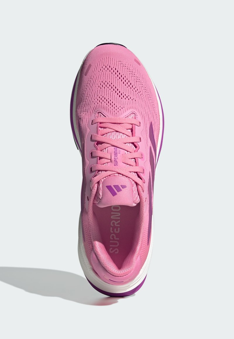 Baskets de course rose clair avec une tige en mesh, accents violets, bout arrondi et épaisse semelle blanche. Lacets et marque "SUPERNOVA" sur la languette.