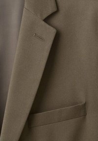 Olivgrünes Sakko mit strukturierter Stoffqualität, Schalkragen und einer einzelnen Brusttasche mit dezenten Zierstichen.