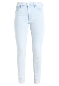 Jeans skinny de tiro alto en azul claro fabricados en denim. Presentan un cierre delantero con botón, presillas para cinturón y dos bolsillos traseros con detalles de costura.