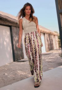 Abito lungo con motivo tie-dye colorato in verde, viola e crema. Abbinato a un top smanicato a coste e sandali bassi.