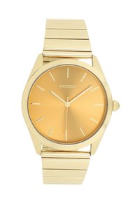 Montre couleur or avec un cadran rond, des marqueurs horaires minimalistes et un bracelet métallique lisse. Le cadran texturé en or améliore la visibilité.