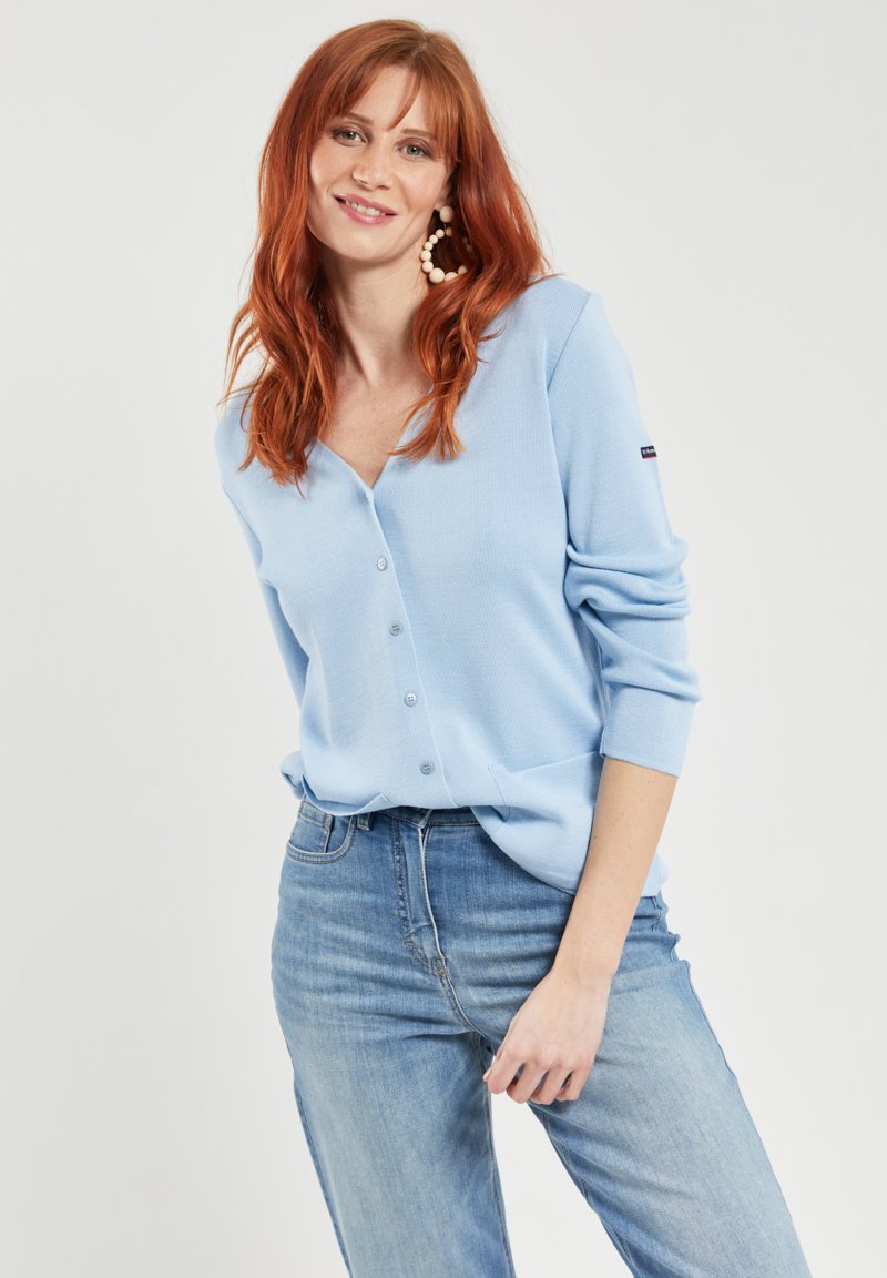 Lichtblauwe, geribbelde cardigan met een v-hals, knopen aan de voorkant en lange mouwen. Gemaakt in combinatie met lichte denim jeans.