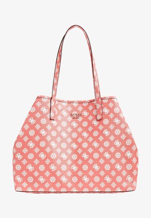 Torba typu tote w kolorze koralowo-różowym z długimi cienkimi uchwytami, pokryta białymi geometrycznymi i kwiatowymi wzorami, z małym metalowym logo Guess na środku.
