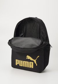Fekete szövet hátizsák arany Puma logóval, cipzáras fő rekesszel és hálós oldalzsebbel. Egyszerű dizájn és tartós kivitel.