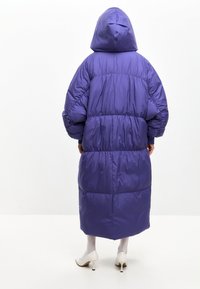 Ljubičasti, podstavljeni dugi kaput s kapuljačom, s naglašenim strukom i elastičnim manžetama. Glatka tekstura, do koljena i s prekomjernim krojem.