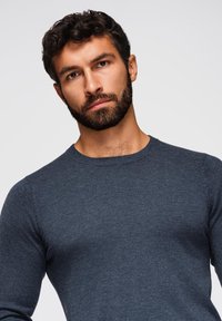 Maglione lavorato a maglia blu scuro con collo rotondo a girocollo, maniche lunghe e silhouette aderente, realizzato in un morbido tessuto testurizzato.