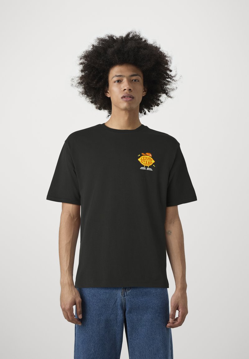 Camiseta de algodón negra de manga corta, con un gráfico colorido de "Lemon Stand" en el lado izquierdo del pecho. Ajuste casual con cuello redondo.