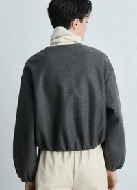 Maglione grigio, corto, con un alto colletto crema. Tessuto morbido e testurizzato con maniche voluminose e un orlo a coste.