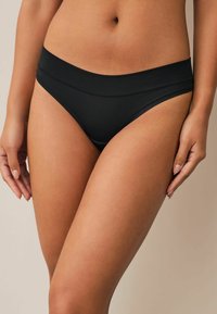Čierne bikiny s hladkou textúrou, s širokým pásom, minimálnym zakrytím a čistým, jednoduchým šitím.