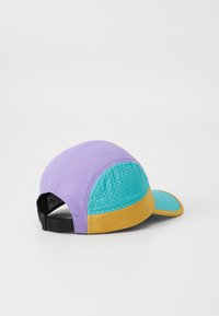 Daugiaspalvė kepurė su violetiniu viršumi, turkio spalvos tinklo paneliu ir geltona kraštine. Yra tekstūruota paviršius ir reguliuojama juostelė gale.