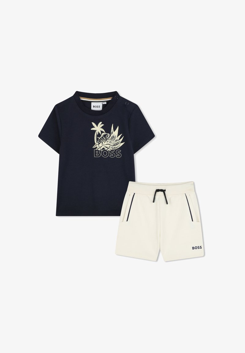 T-shirt en coton navy avec un motif de palmier et floral, arborant le logo "BOSS" ; associé à un short crème, avec cordon de serrage réglable et deux poches.
