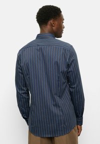 Marineblaues Langarmhemd mit dünnen vertikalen Streifen in Blau und Weiß, mit geknöpften Manschetten und abgerundetem Saum. Glatte Stofftextur.