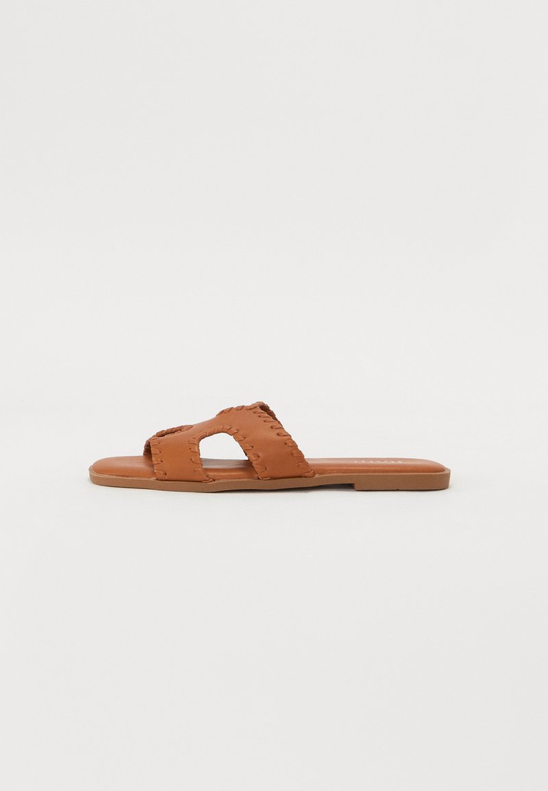 Brune lærskli sandal med åpen tå design, dekorativ søm og flat såle. Enkel, uforfalsket form.