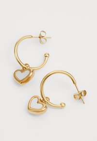 Gold hoop earrings featuring a heart charm. The charm has a hollow heart shape with a smooth, shiny surface and a secure post-back closure.