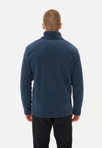 Pullover in pile blu navy con colletto alto, caratterizzato da un motivo testurizzato a griglia e maniche lunghe, visto da dietro.