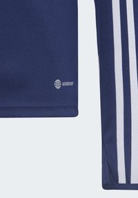 Maglietta sportiva navy con tessuto testurizzato, logo bianco con la scritta "AEROREADY" e tre strisce bianche lungo una manica.