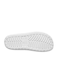 Semelle de chaussure en caoutchouc blanc avec un motif de grip texturé, présentant des indentations circulaires et angulaires sur la surface pour une meilleure adhérence.