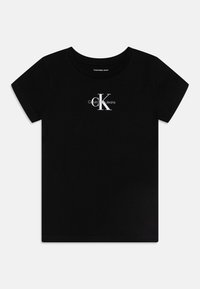 Melna kokvilnas t-kreklu ar apaļu kaklu un īsām piedurknēm. Iekļauj balto logotipa dizainu ar "Calvin Klein Jeans" zem burta "K."