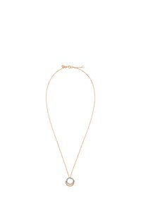 Złota naszyjnik z cienkim łańcuchem i okrągłym zawieszeniem z przezroczystym kamieniem otoczonym metalową obręczą.
