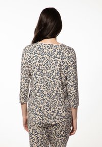 Luxe loungewear set met luipaardprint en driekwart mouwen, gemaakt van zachte stof in beige en donkergrijze kleuren, met een ontspannen pasvorm.