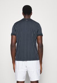 Mörkblå randig t-shirt för män med kort ärm och rundad halsringning, tillverkad av texturerat tyg. Har vertikala vita ränder och logotypdetaljer.